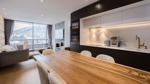 A modern kitchen with a wooden dining table, built-in appliances, and a large window overlooking a snowy landscape. - Ground floor, balcony, fireplace or stove, tv, 52m², La Clusaz (La Clusaz)