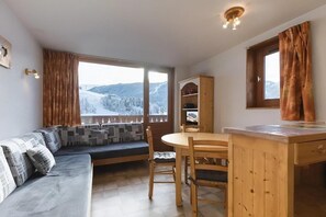 A cozy room with a sofa, a wooden dining table, and a view of a snowy landscape.