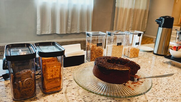 A breakfast buffet with various food items and a cake on a glass plate. - Unity Hotel Campinas (Campinas)