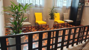 A seating area with yellow chairs and potted plants, a vending machine, and a black refrigerator. - Unity Hotel Campinas (Campinas)