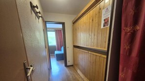 A hallway with wooden paneling, a door with a handle, and a sign on the wall. - 100m from ski slopes, 1st floor, balcony, 21m², Tignes (Tignes)