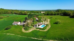 An aerial view of a rural property with a swimming pool, a small house, and expansive green fields. - Spacious cottage with air conditioning, wood fire & panoramic views - pool shared (Paulhiac)