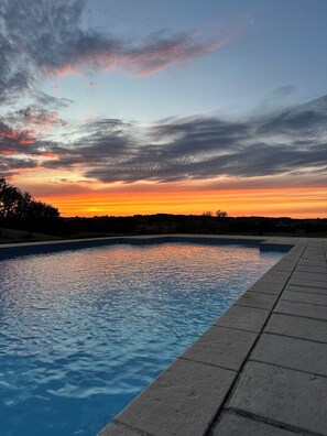 A swimming pool with a sunset view, surrounded by a stone deck. - Spacious cottage with air conditioning, wood fire & panoramic views - pool shared (Paulhiac)