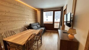 Un ambiente compatto con un tavolo da pranzo in legno, sedie, un divano e una TV su un mobile in legno.