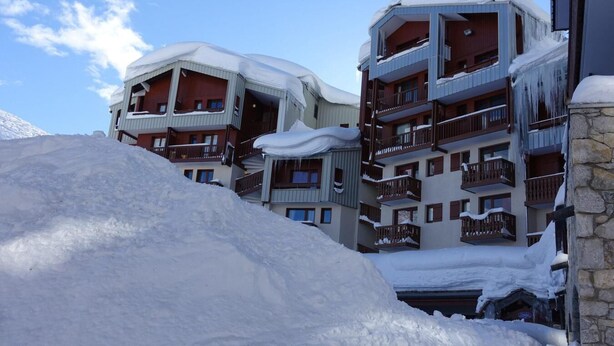Un hotel a più piani con balconi e un paesaggio innevato.
