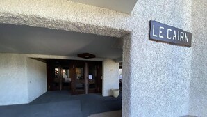 L'ingresso di Le Cairn, con facciata strutturata, una targa informativa e un'area d'ingresso piastrellata.