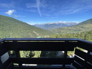 Een balkon met uitzicht op een bergachtig landschap, inclusief een vallei en verre toppen.