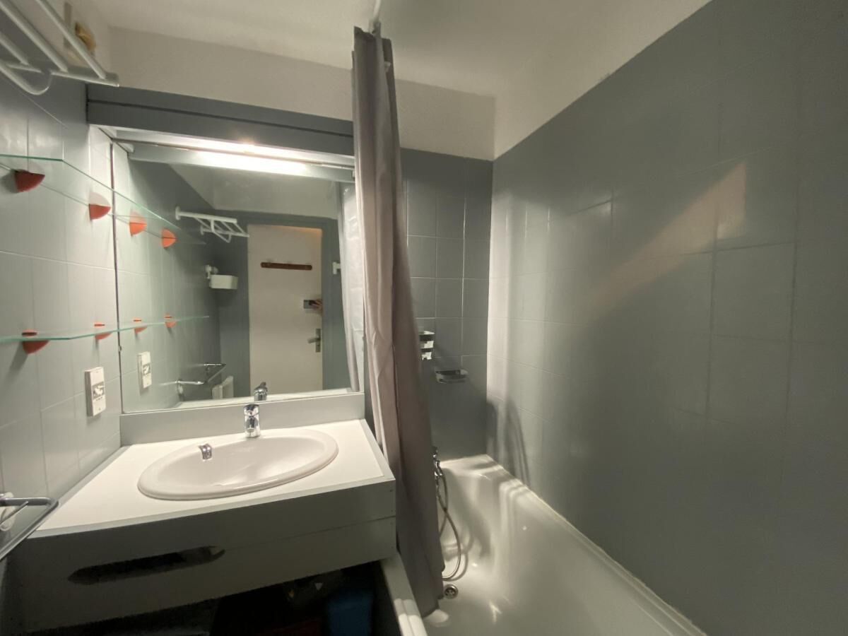 A bathroom with a white sink, a mirror, and a shower area.
