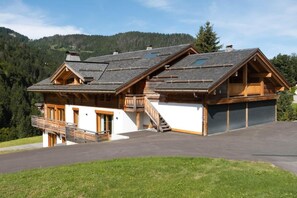 A two-story wooden house with a balcony, a garage, and a driveway. - 1st floor, view mountain, balcony, fireplace or stove, tv, ski locker, 119m², La Clusaz (La Clusaz)