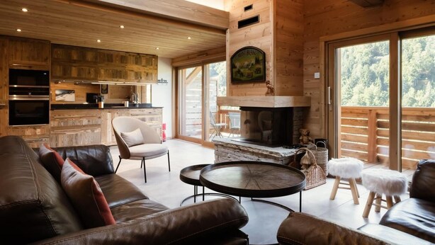 A cozy cabin interior with a fireplace, leather furniture, and a kitchen area. - 1st floor, view mountain, balcony, fireplace or stove, tv, ski locker, 119m², La Clusaz (La Clusaz)