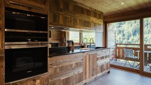 A modern kitchen with wooden cabinetry and a built-in oven. - 1st floor, view mountain, balcony, fireplace or stove, tv, ski locker, 119m², La Clusaz (La Clusaz)