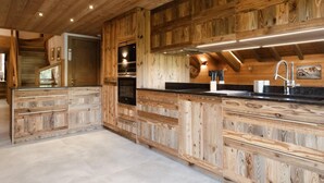 A modern kitchen with wooden cabinetry and a central island. - 1st floor, view mountain, balcony, fireplace or stove, tv, ski locker, 119m², La Clusaz (La Clusaz)