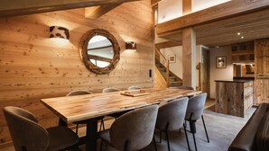 A wooden interior with a large dining table and chairs, a circular mirror, and a staircase leading to another room. - 1st floor, view mountain, balcony, fireplace or stove, tv, ski locker, 119m², La Clusaz (La Clusaz)