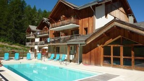 Een houten chalet met een zwembad en meerdere balkons.