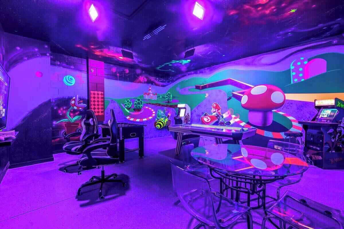 Une pièce comprenant une table de jeux, une grande décoration en forme de champignon et une fresque murale colorée.