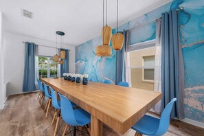 A dining area with a wooden table, blue chairs, and wicker pendant lights. - 5BR Villa+ Spa & Pool Oasis+GameRoom+Themed Rooms (Davenport)