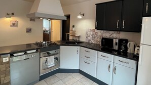 A modern kitchen with a gas stove, oven, microwave, and a refrigerator. - 5-person apartment with outdoor area (Saint-Maurice-sur-Moselle)