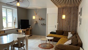 A living room with a sofa, a TV, a dining table with chairs, and a small side table. - 5-person apartment with outdoor area (Saint-Maurice-sur-Moselle)