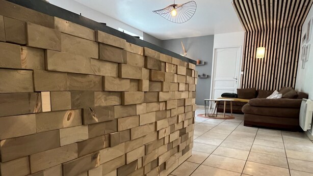 A modern living room with a textured wall, a sofa, and a coffee table. - 5-person apartment with outdoor area (Saint-Maurice-sur-Moselle)