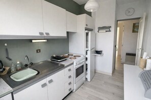 A modern kitchen with white cabinets, a stainless steel sink, and a built-in oven. - Horizon Bleu with terrace in Sainte-Maxime (Sainte-Maxime)