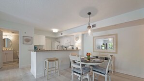 A modern kitchen with white cabinets, a dining area with a round table and chairs, and a large mirror on the wall. - Fantastic 2-bedroom 2 bath condo for Seasonal Rent in Tequesta Fla (Tequesta)
