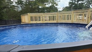 Une piscine avec une terrasse en bois et un toboggan.