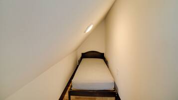 A small, narrow room with a single bed and a sloped ceiling.
