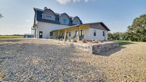 Ein zweigeschossiges Haus mit überdachter Veranda und einem Schotterweg.