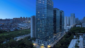 A high-rise building with a modern glass facade, surrounded by other high-rise buildings and a park area. - Days Inn By Wyndham Kunming Wujiaba (Kunming)