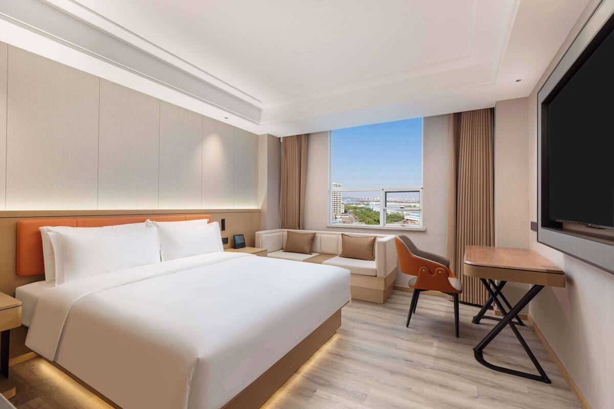 Ein Hotelzimmer mit einem großen Bett, einem Sofa, einem kleinen Tisch und einem Fernseher.