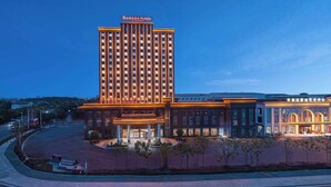 Um hotel com uma torre vertical imponente e um edifício anexo com sinalização iluminada.