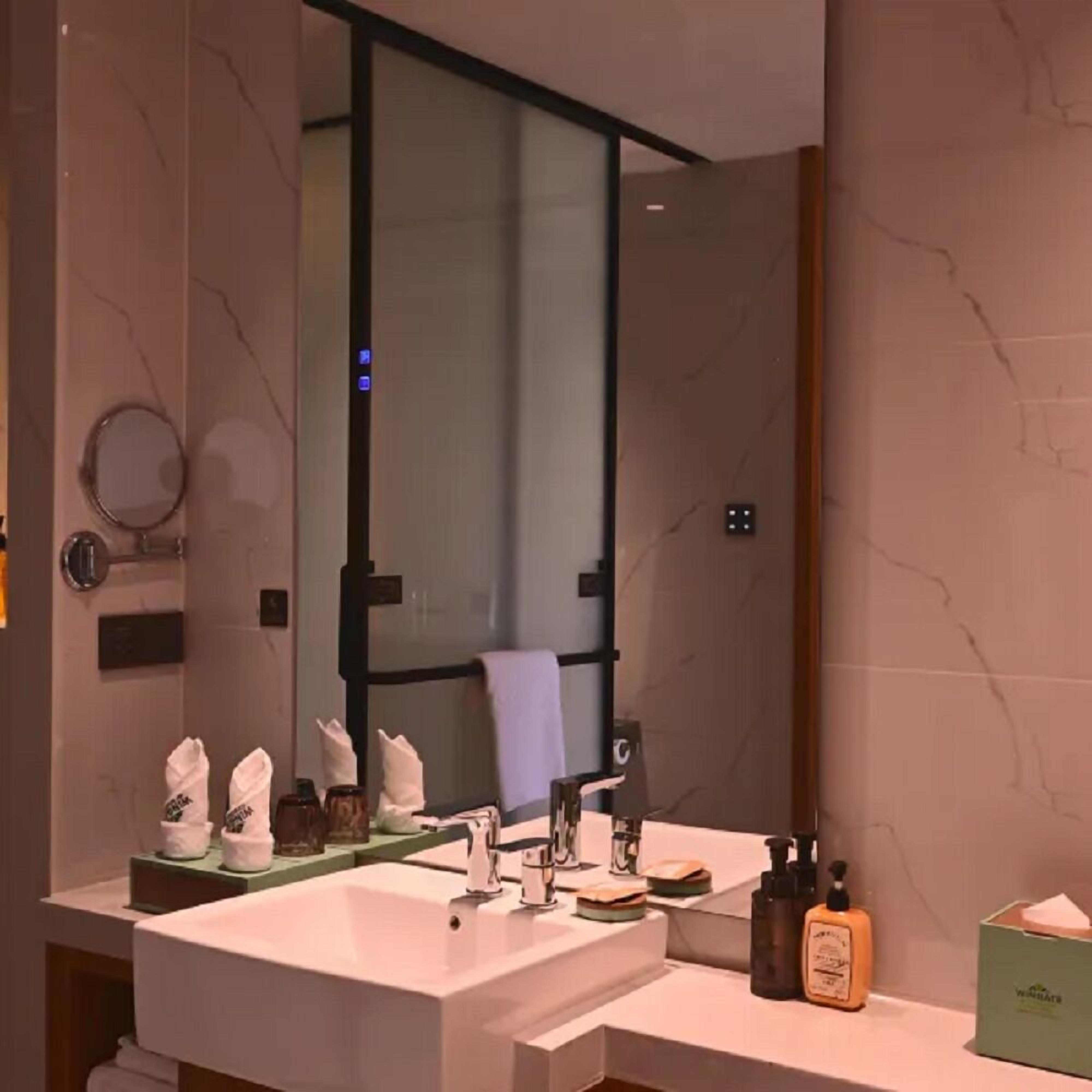A modern bathroom with a large mirror, a sink, and a towel rack.