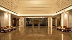 Un'ampia hall con soffitto alto, pareti in marmo e pavimento lucido.