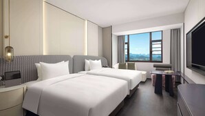Quarto de hotel com duas camas, uma escrivaninha, uma cadeira, uma televisão e uma janela grande com vista para as montanhas.