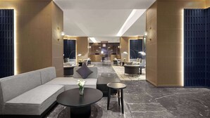 Um hall moderno com sofá, mesa de centro e área de estar, com balcão de recepção e um lustre.