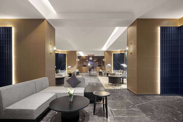 A modern lobby with a sofa, coffee table, and seating area, featuring a reception desk and a chandelier. - Wingate By Wyndham Guilin Lingui (Guilin)