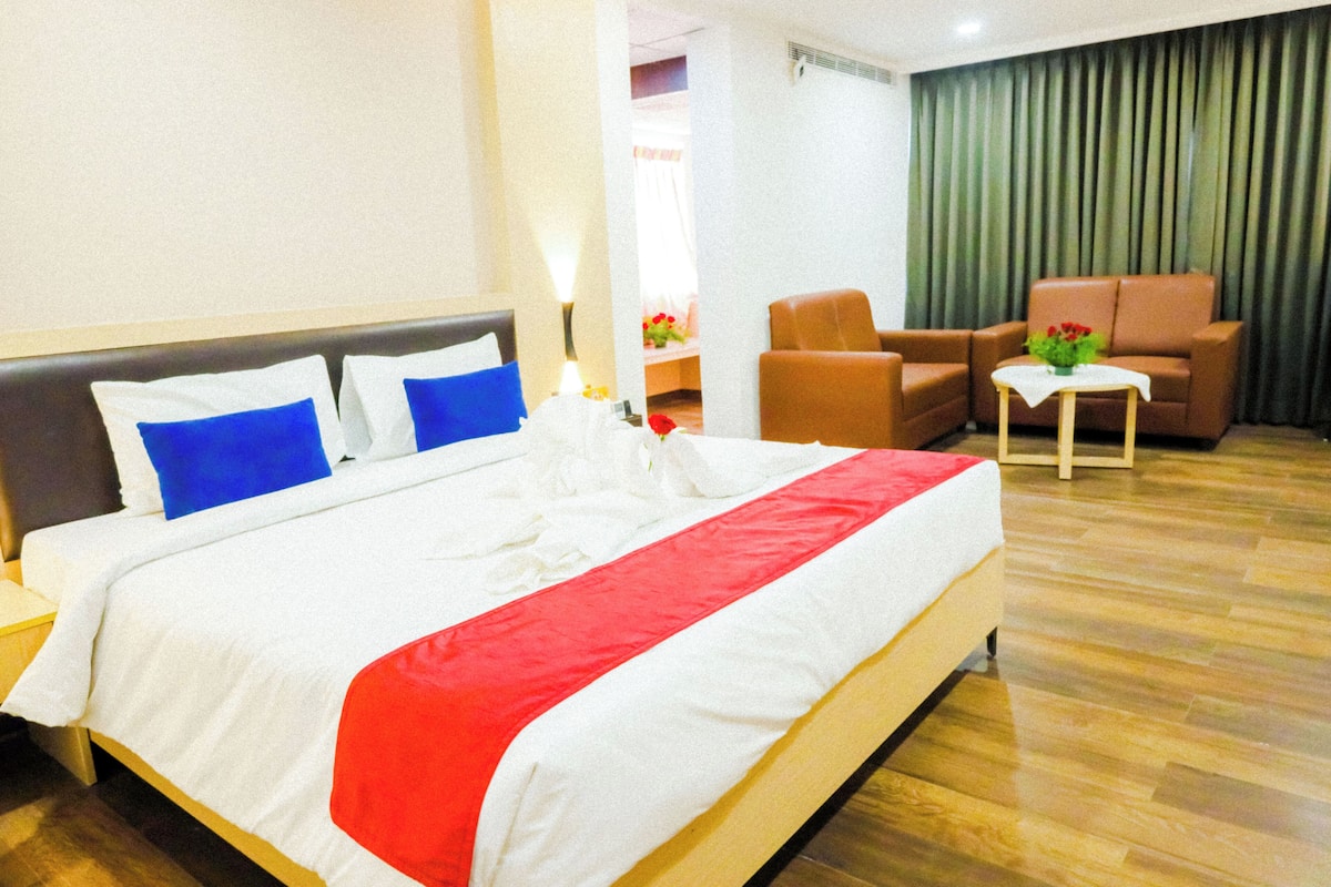 Relax in a stylishly designed room with a comfortable bed, seating area, and beautiful flowers.