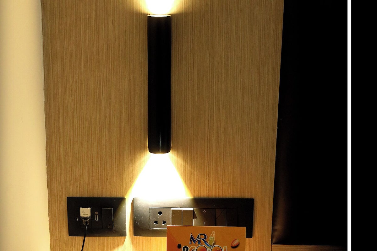 A wall-mounted light fixture illuminates a room's interior, featuring a central bulb and two smaller lights.