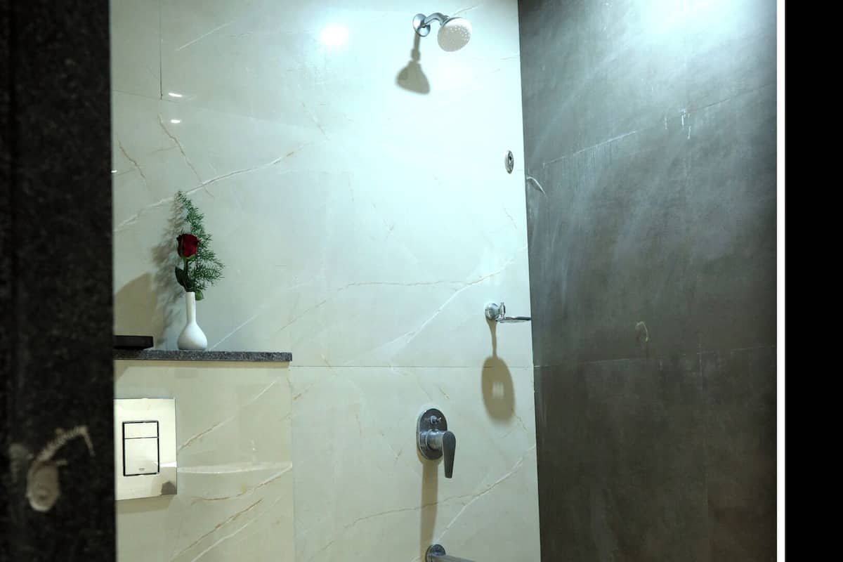 Bathroom features a shower area with handheld showerhead and a faucet, along with a countertop with a vase and a rose.