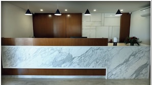 A reception area with a marble counter, wooden paneling, and pendant lighting. - Sri Sri Sri Excellency  (Khammam)
