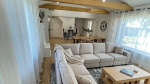 A modern living room with a beige sectional sofa, a wooden coffee table, and a dining area in the background. - Relax on the Lake - 180 degree Views (North East)