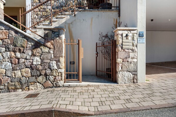 A stone wall, a metal gate, and a staircase leading to a building entrance.