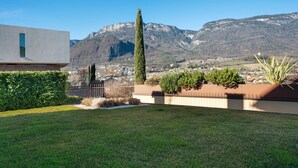 A modern building with a flat roof, a well-maintained lawn, and a mountain backdrop.