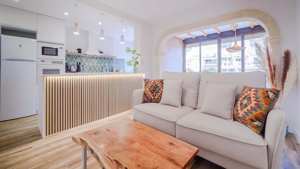 A modern kitchen with white appliances, a wooden island, and a seating area with a sofa and a coffee table.