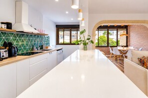 Eine moderne Küche mit einer zentralen Kochinsel, weißen Schränken und einer grünen Spritzschutzwand.