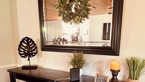 A dark wooden desk with two black chairs, a potted plant, a small sign, and a candle.