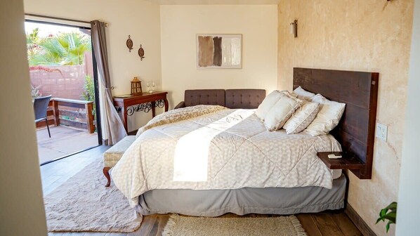 Un dormitorio con una cama grande, una mesita de noche, una pequeña mesa con velas y vistas al exterior.