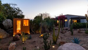 A desert garden with a wooden structure and a modern building.