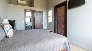 A bedroom with a bed, a television, a wardrobe, and a bathroom visible through an open door.