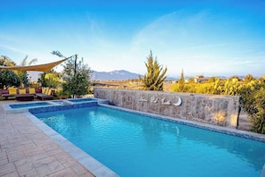 Ein Pool mit Steinmauer und Bergblick im Hintergrund.